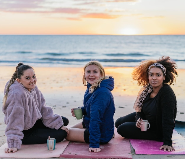 日没時にお茶を飲みながらマットの上に座って回る異なる民族の3人の女性