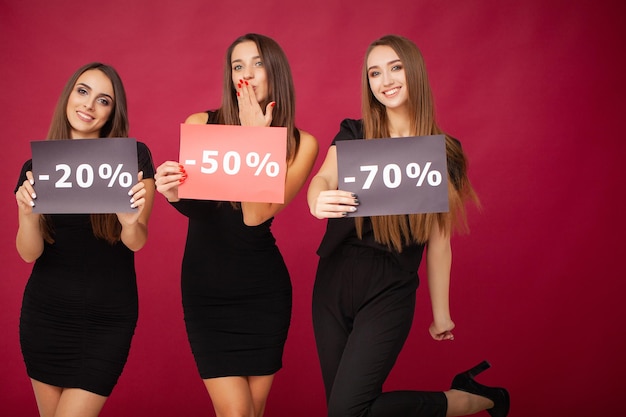 Three women holding discount posters