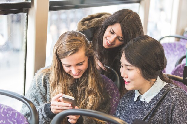 バスでスマートフォンを探している3人の女性