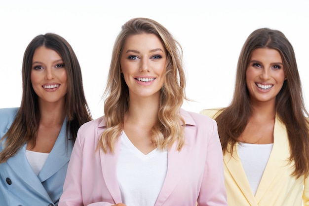 three women in pastel suits posing over white background