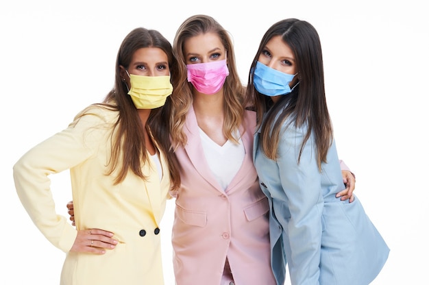 three women in pastel suits posing over white background