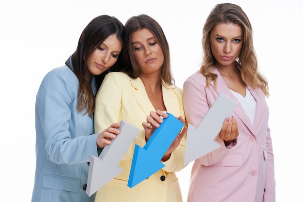 Three women in pastel suits posing with arrows over white background