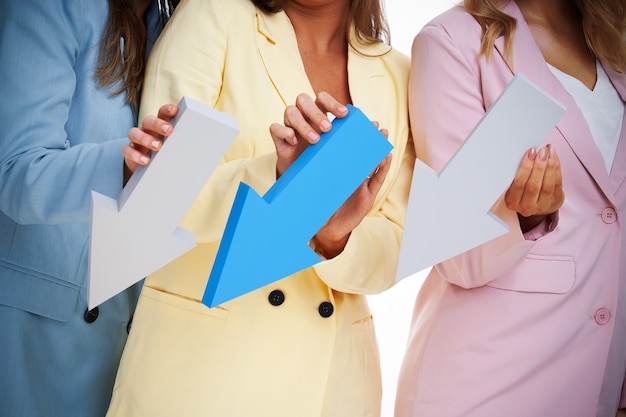 Three women in pastel suits posing with arrows over white background