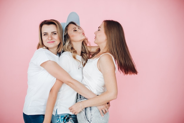 Three women in summer clothes have a lot of fun on a birthday party, picture isolated on pink background