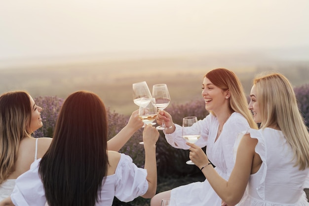 Three women toasting glasses of lavender in a lavender field