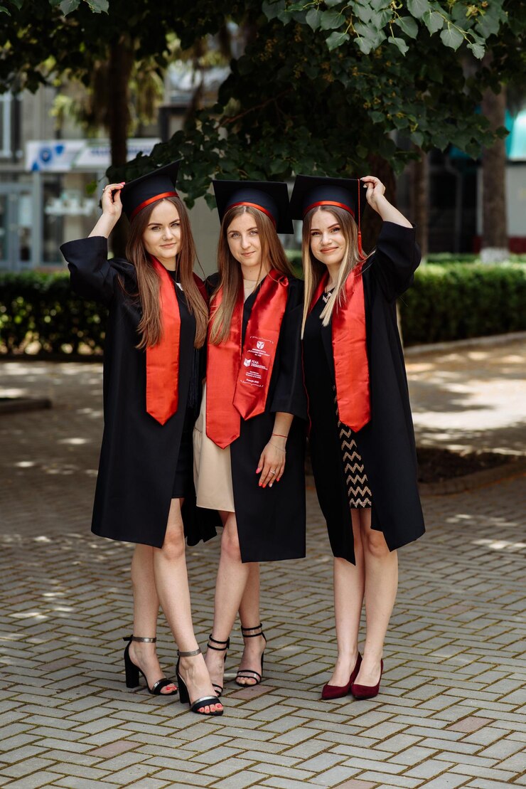 Photo three women wearing graduation caps stand on a sidewalk