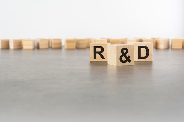 Three wooden blocks with letters R and D with focus to the single cube in the foreground in a conceptual image on grey background