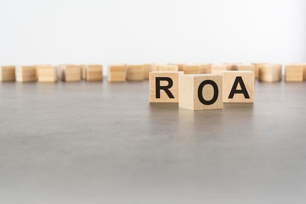 Three wooden blocks with letters ROA with focus to the single cube in the foreground in a conceptual image on grey background