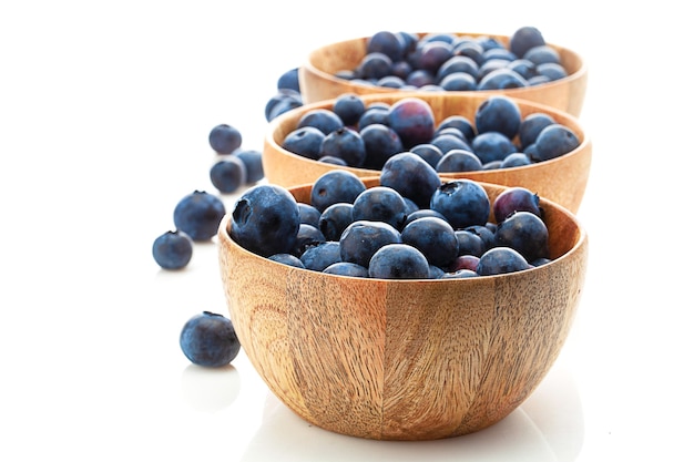 Three wooden bowls with blueberry isolated on white background