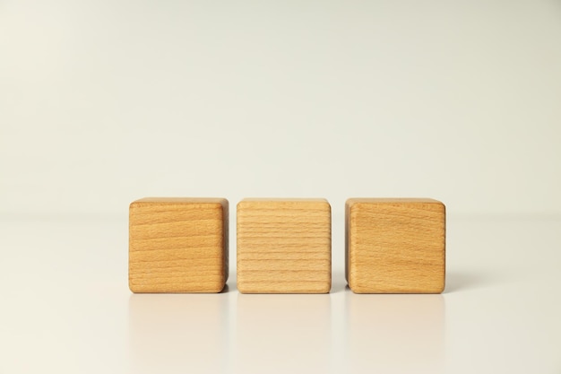 Three wooden cubes on white table close up