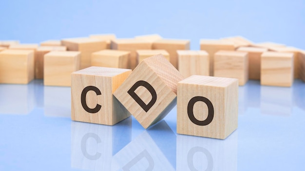 Three wooden cubes with the letters CDO on the bright surface of a pale lilac table the inscription on the cubes is reflected from the surface table CDO short for collateralized debt obligations