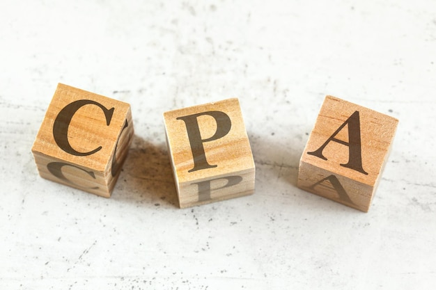 Photo three wooden cubes with letters cpa stands for cost per action acquisition on white board..