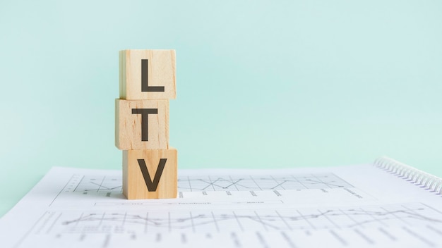 Three wooden cubes with letters LTV, on white white paper with diagram, business concept. LTV - short for lifetime value