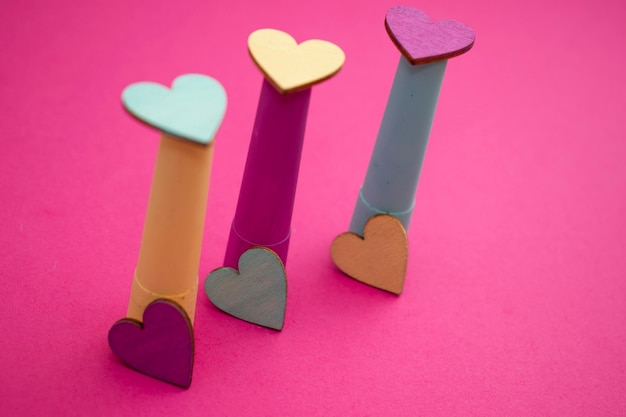 Three wooden hearts are on a pink background with the word love on them.