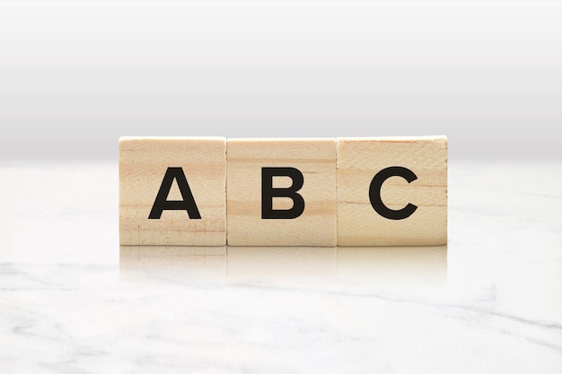 Photo three wooden tiles spelling abc against a classy white marble background