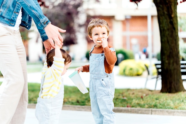 Photo three year old boy eating an afternoon snack in a park with his family