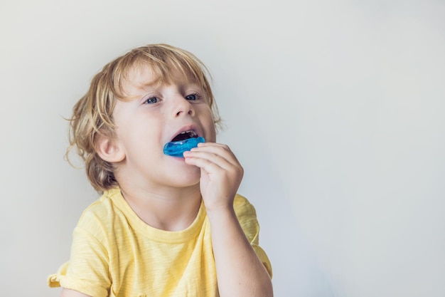 3歳の男の子は、口呼吸の習慣を照らすために筋機能トレーナーを示しています。成長する歯を均等にし、噛み付きを修正するのに役立ちます。舌の位置を修正します