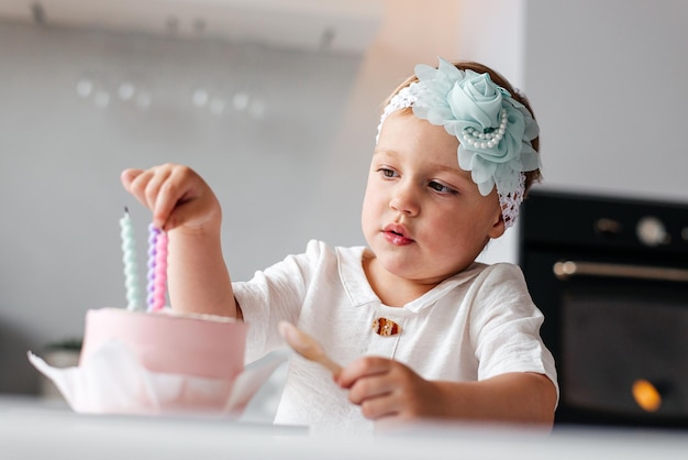 3歳の女の子が誕生日のケーキのキャンドルを吹き飛ばす 誕生日の記念日を祝う子供