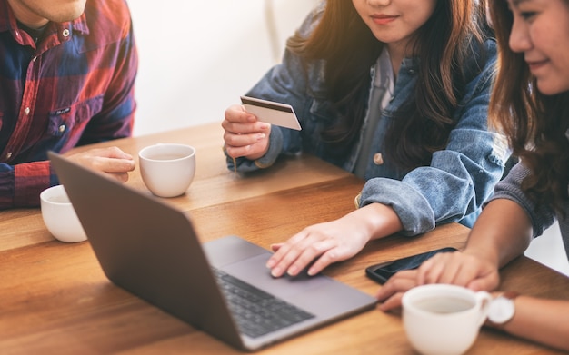 Three young asian people use credit card for purchasing and shopping online