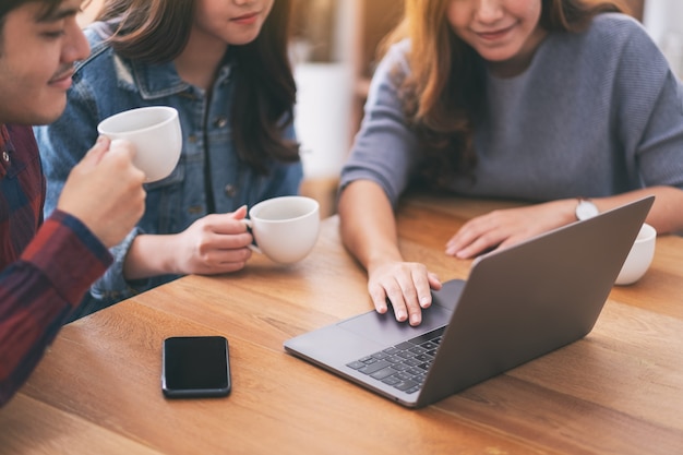 Three young asian people using and looking at the same laptop computer during a meeting