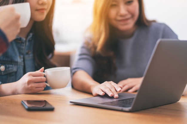 Three young asian people using and looking at the same laptop computer during a meeting