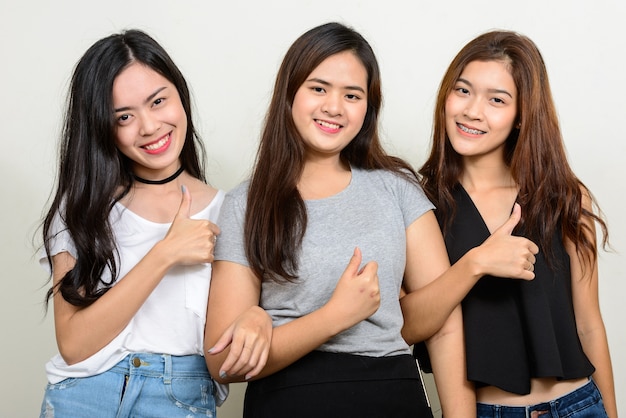 three young Asian women as friends together against white space