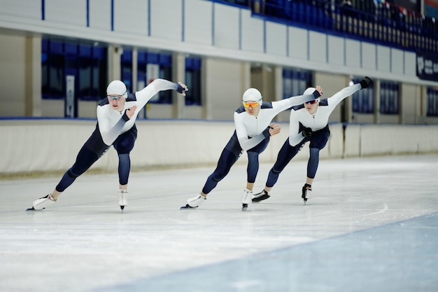 Фото Трое молодых спортсменов в спортивной форме, коньках и защитных очках