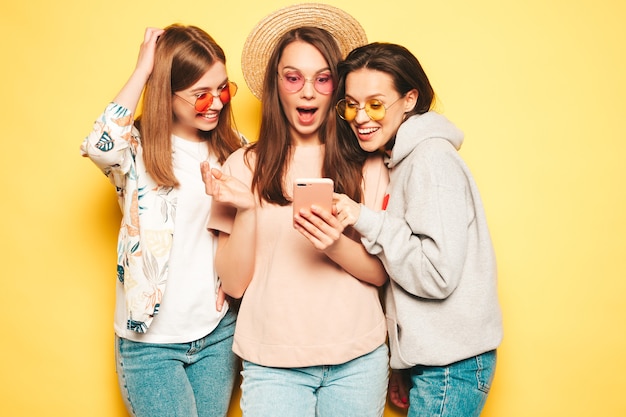 Three young beautiful smiling hipster female in trendy same summer clothes