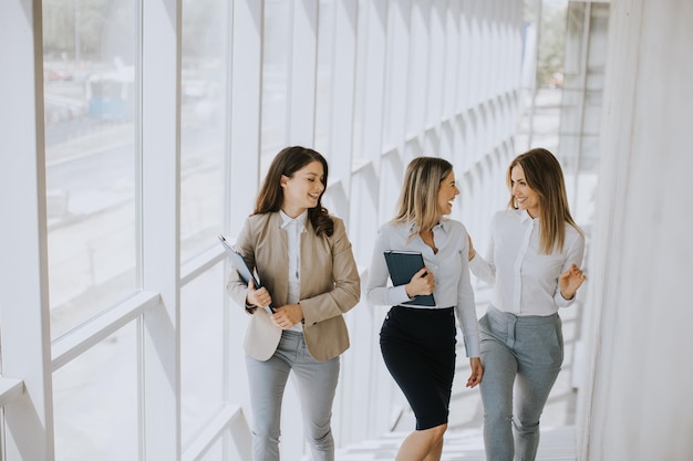 Three young business women walking on stairs in the office hallway