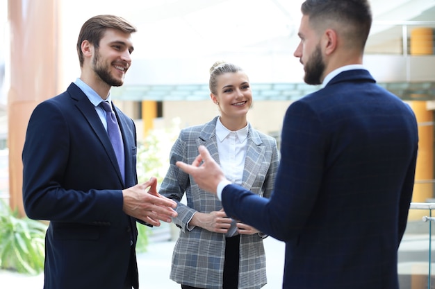 Three young businessmen standing discussing business at an office meeting.