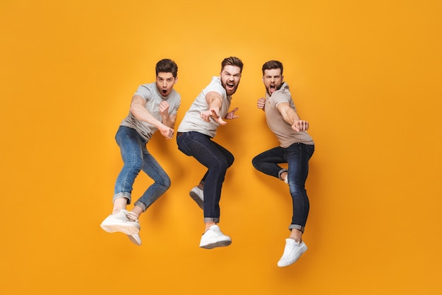 Three young cheerful men jumping together