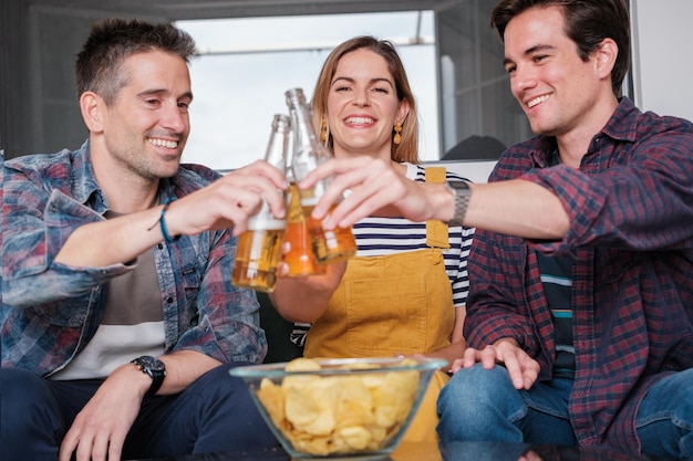 Three young friends toasting with beer and smiling Concept lifestyle friendship fun