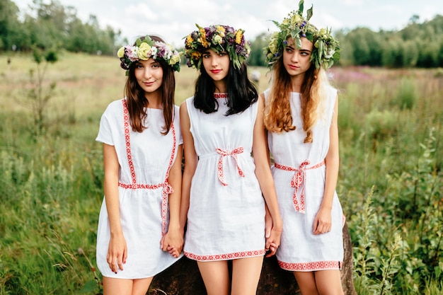 Photo three young girl slavonic appearance in etno folk white traditional dresses outdoor summer portrait.