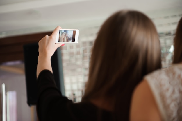 3人の若い女の子がレストランでselfie写真をやっています。