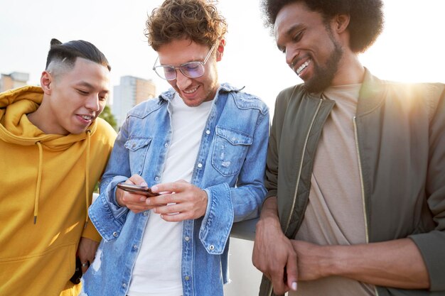 Трое молодых людей стоят и пролистывают мобильный телефон