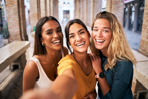 three young smiling 20s young girls in summer clothes women taking selfie self portrait photos on smartphone
