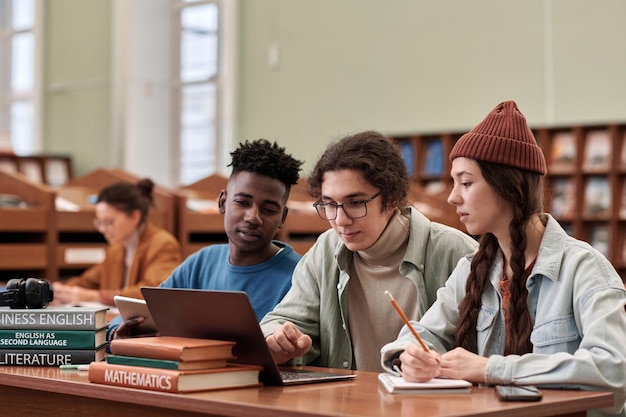 Photo three young students using laptop