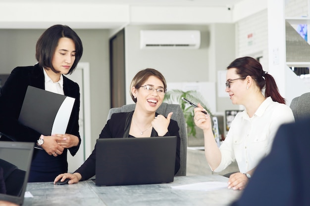 写真 オフィスで3人の若い成功したビジネスウーマンが一緒にプロジェクトに喜んで取り組んでいます