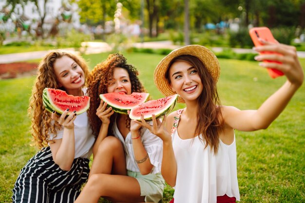 写真 3人の若い女性が暑い夏の日に一緒に楽しんでスイカを食べています