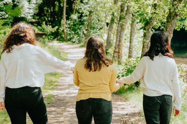 Three young woman holding hands together walking to the future trough a path, friendship care concept