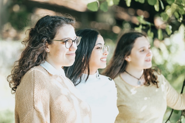 Three young woman looking with confidence to the horizon during a sunny day, future students concept, friendship and care, woman leadership