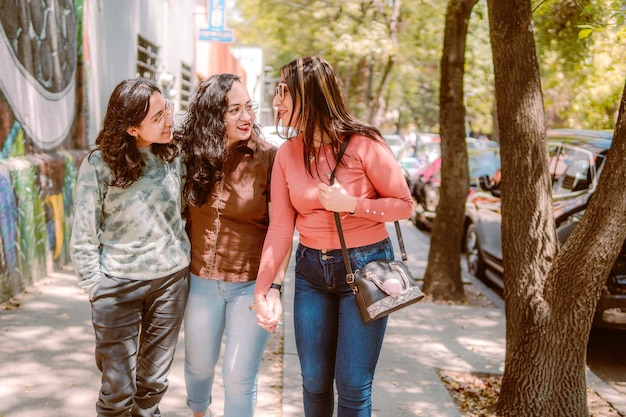 Three young women are walking down the street they are smiling playing and having a good time