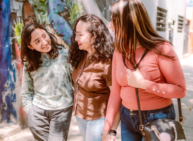 Three young women are walking down the street they are smiling playing and having a good time