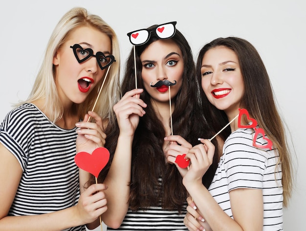 Three young women holding paper party sticks