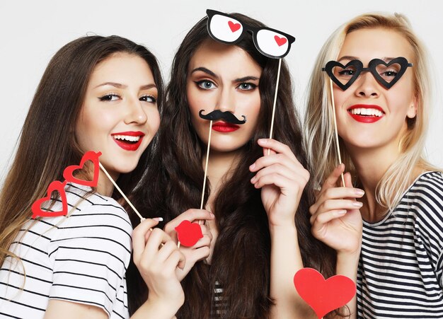 Photo three young women holding paper party sticks