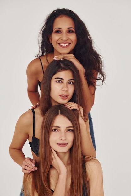 Three young women in lingerie together indoors White background