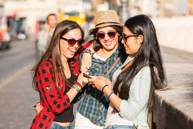 Три молодые женщины со смартфоном в городе