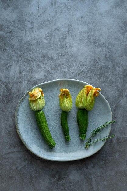 Three zucchini flowers on plate on stone background