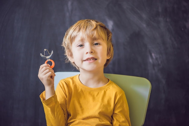 3歳の男の子は、舌構音障害を刺激するためのビーズ付きの前庭プレートプレートを示しています