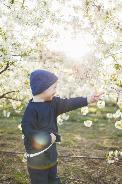 A threeyearold boy runs through a blooming garden Cheerful emotional child is walking in the park